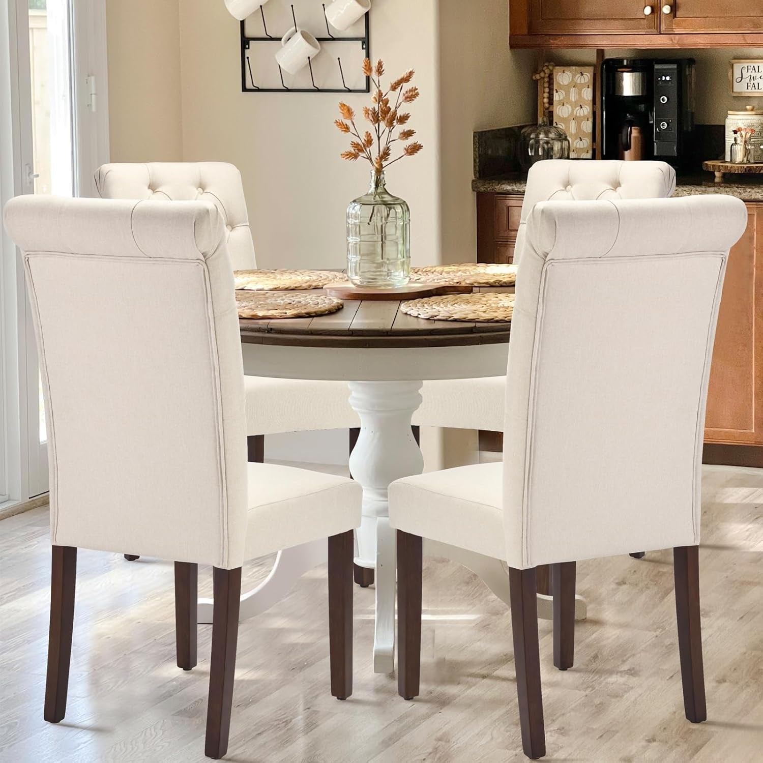 Dining room with a wooden table and white chairs, featuring a vase with flowers on the table.