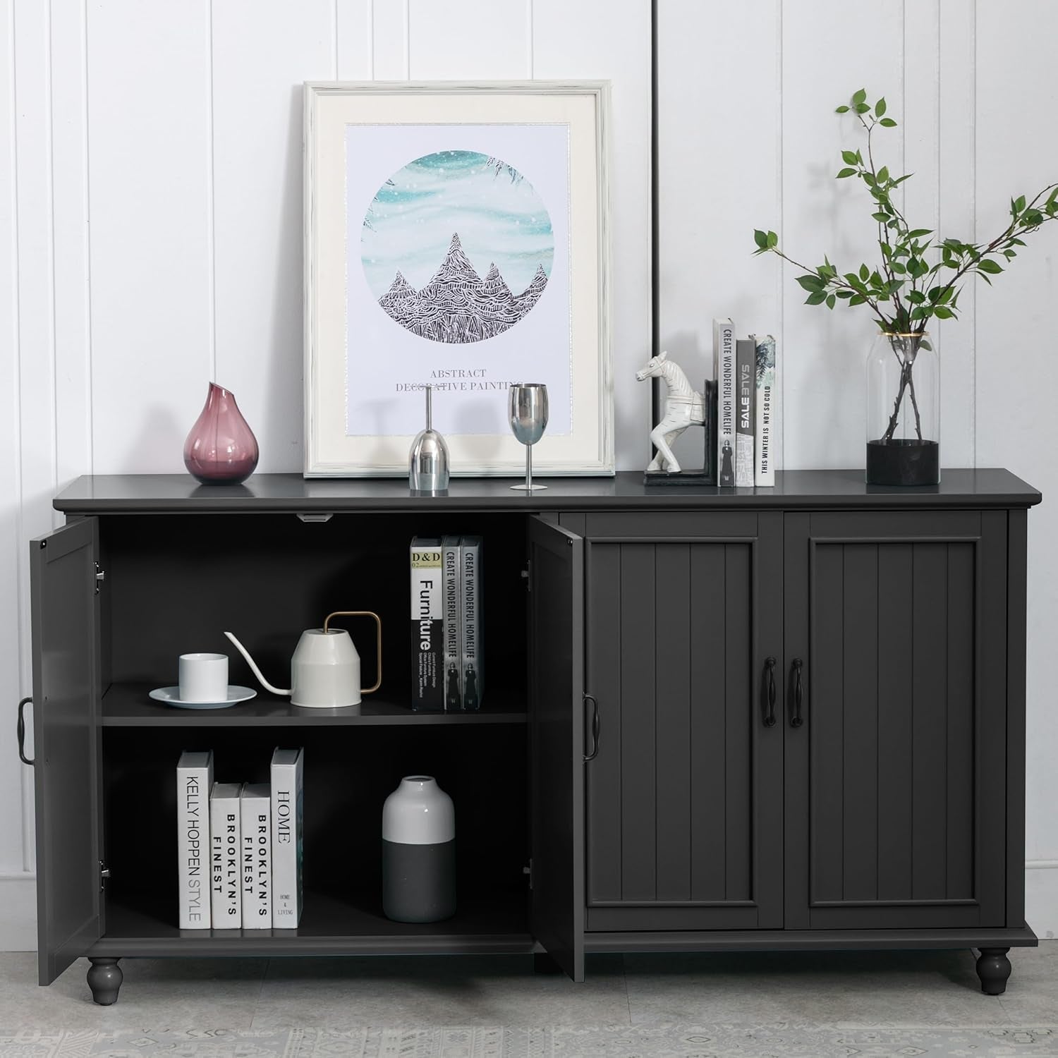 Black sideboard with open doors displaying books, a vase, and other decorative items against a white wall.