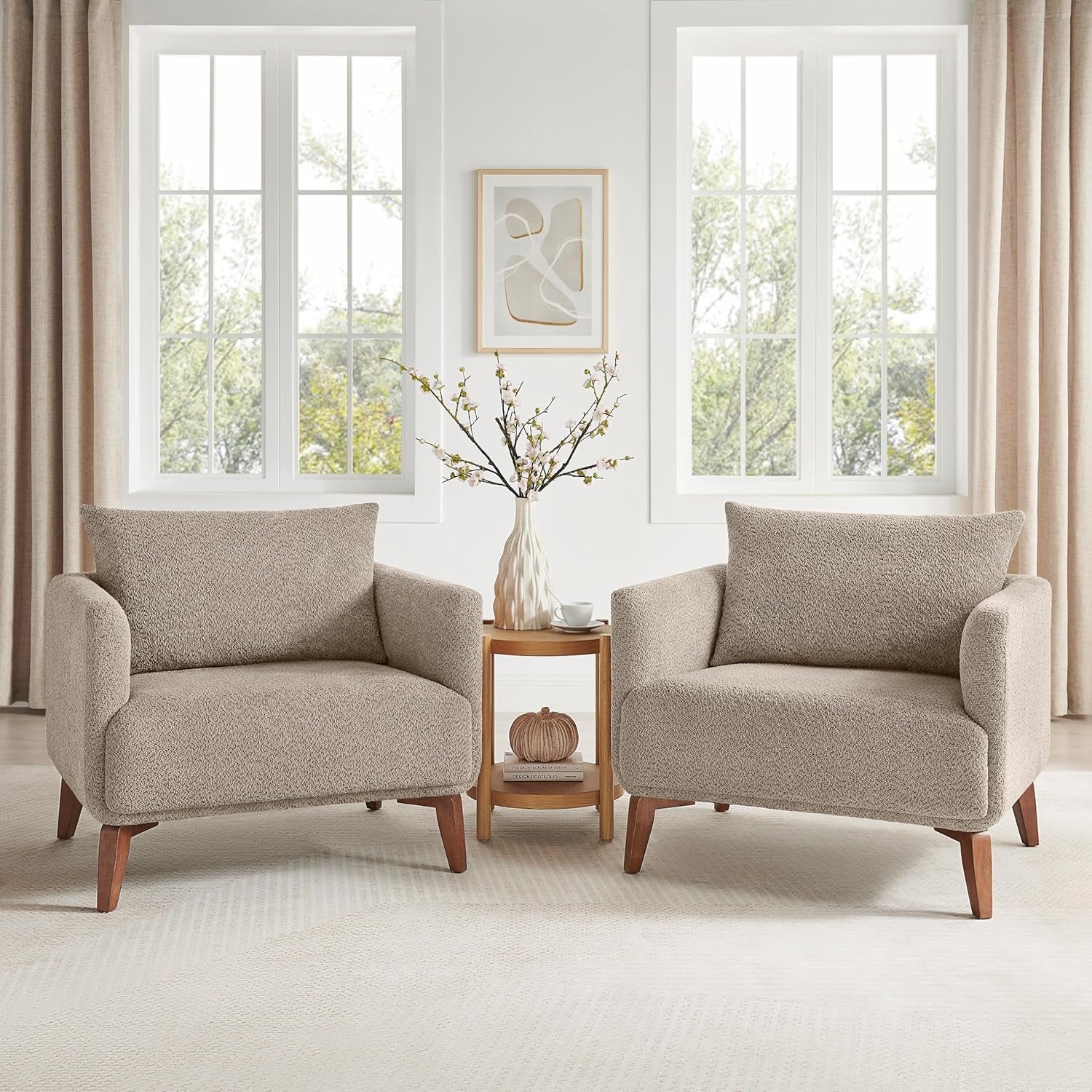 Two beige armchairs in a bright living room with large windows.