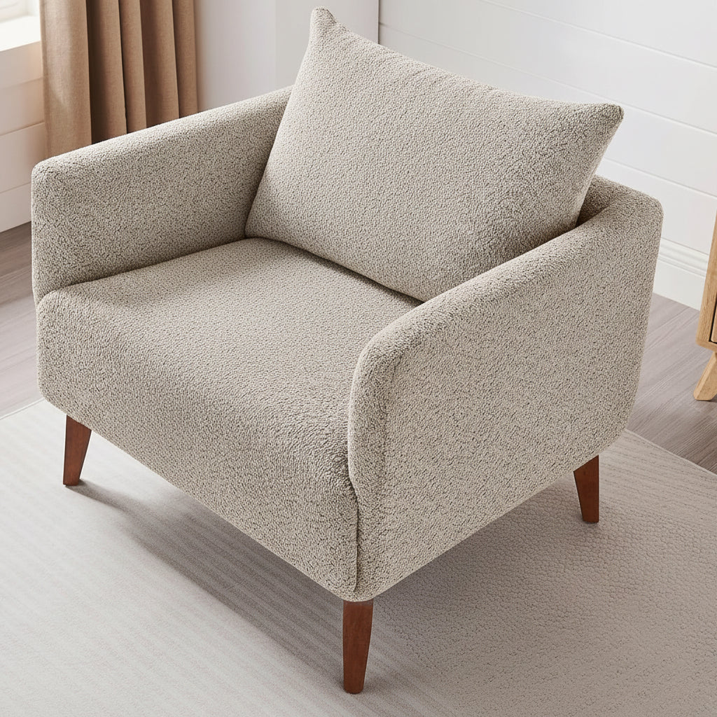 Person sitting on a beige armchair reading a book in a cozy room.