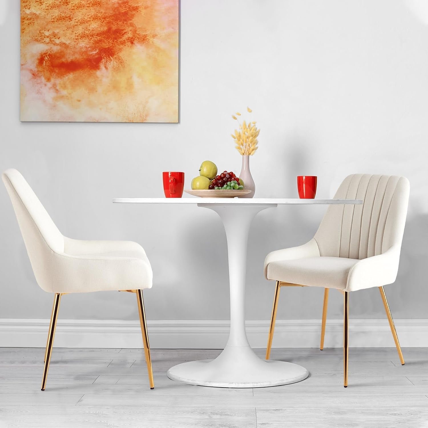 Modern dining set with white table and chairs against a gray wall with abstract art.