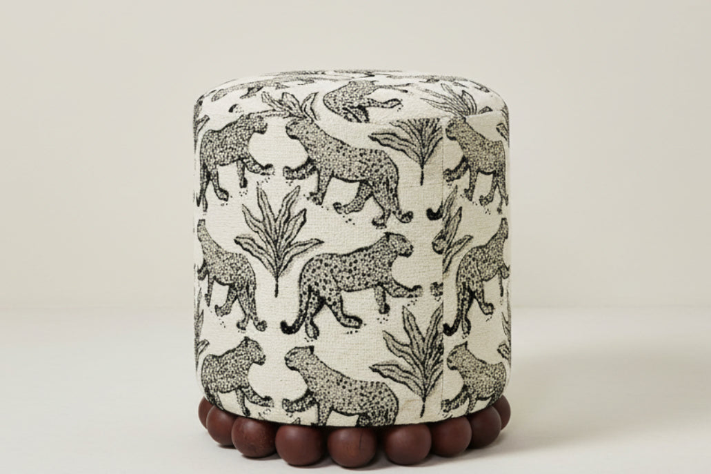 Round ottoman with animal pattern and wooden feet on a white background
