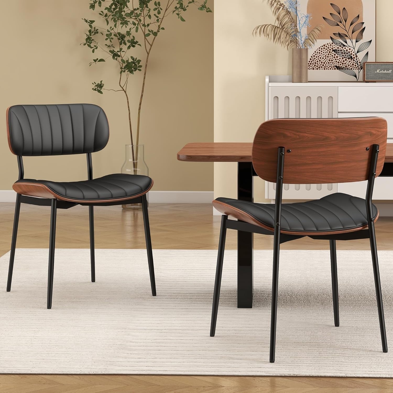 Two modern chairs with black seats and wooden backrests in a room with a table and decor.