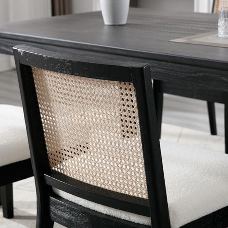 Dining chair with black frame and woven backrest in front of a wooden table.