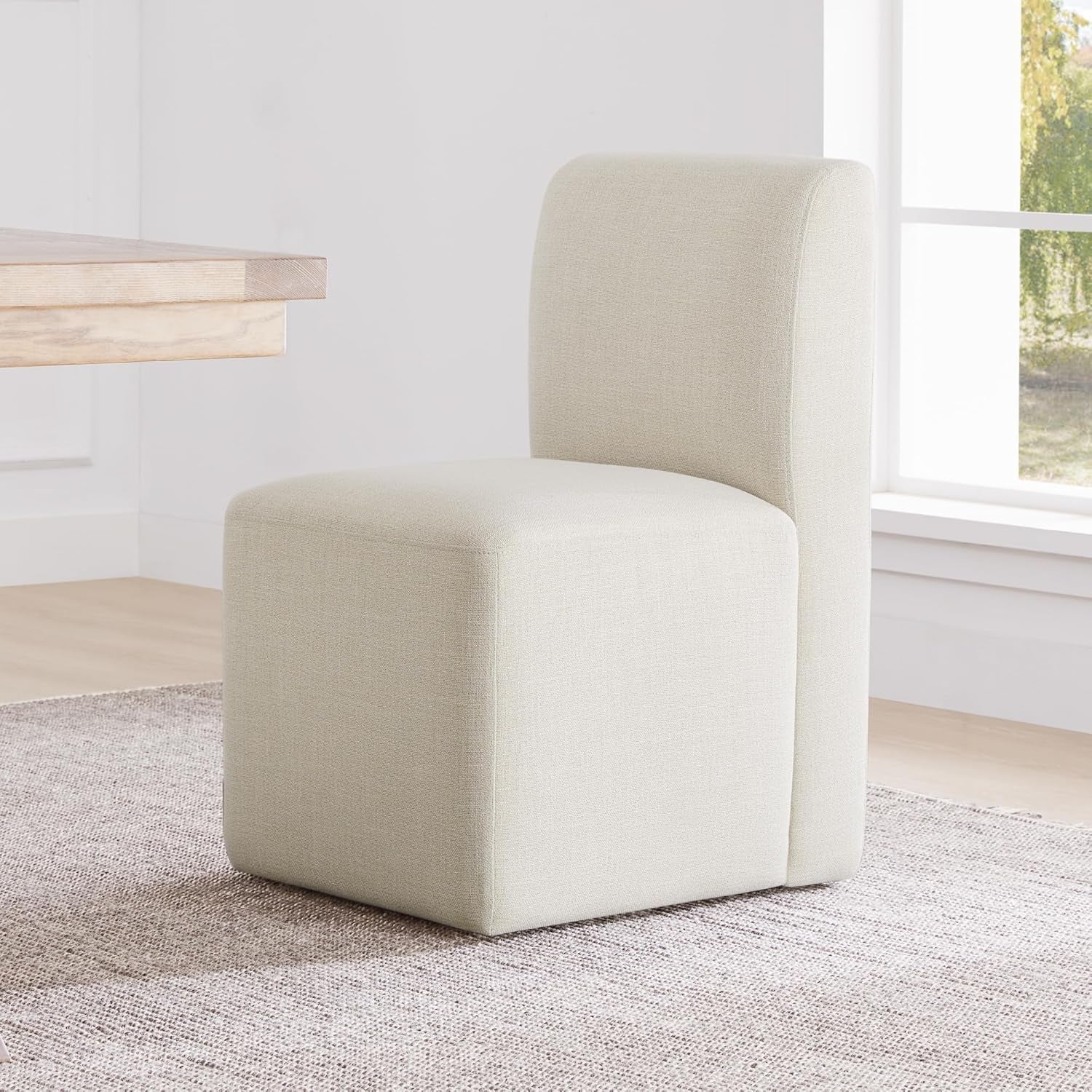 Beige chair in a room with a window and wooden table.