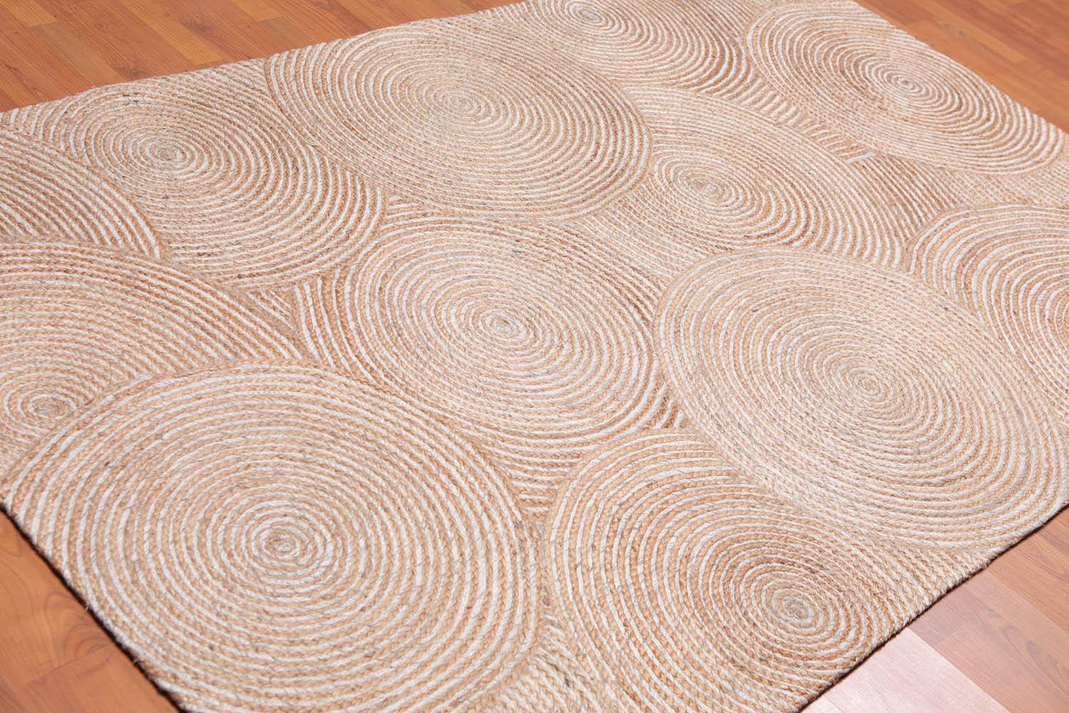 Beige woven rug with circular pattern on a wooden floor