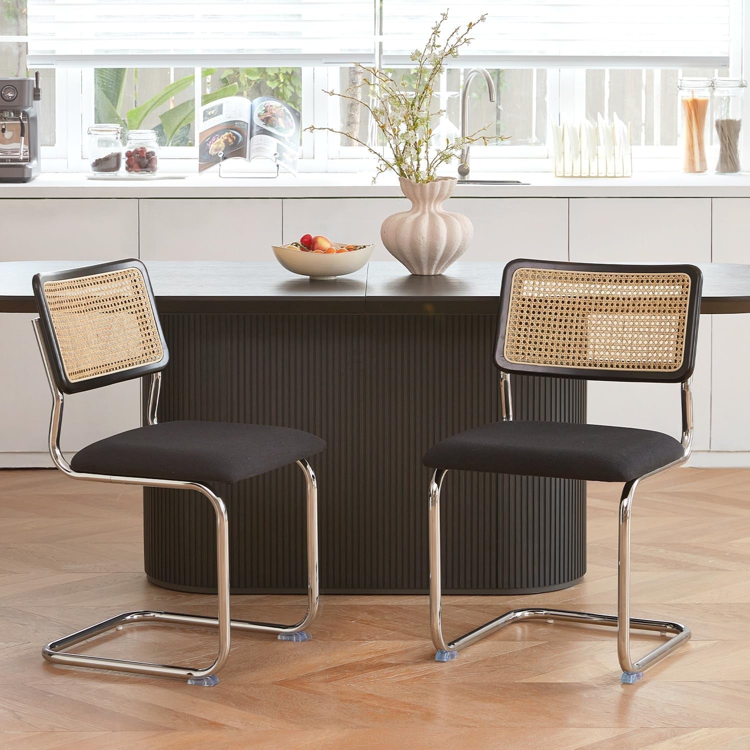 Two black bar stools with wicker backs in a kitchen setting.