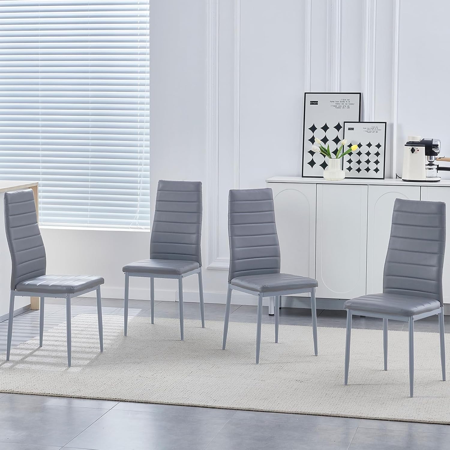 Four gray chairs in a modern dining room setting with a white cabinet and decor.