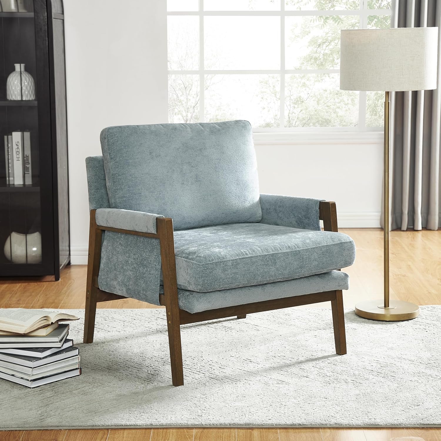 Blue armchair in a living room setting with a lamp and books in the background.