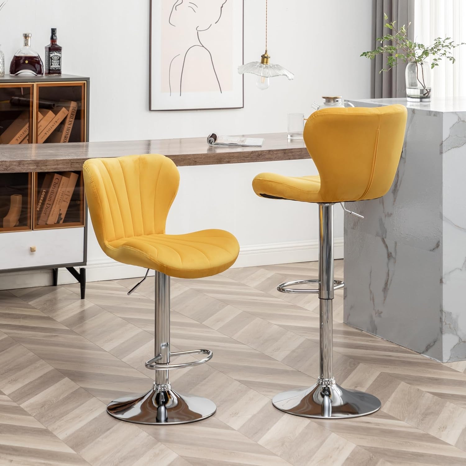 Two yellow bar stools in a modern kitchen setting with marble island and wooden cabinets.