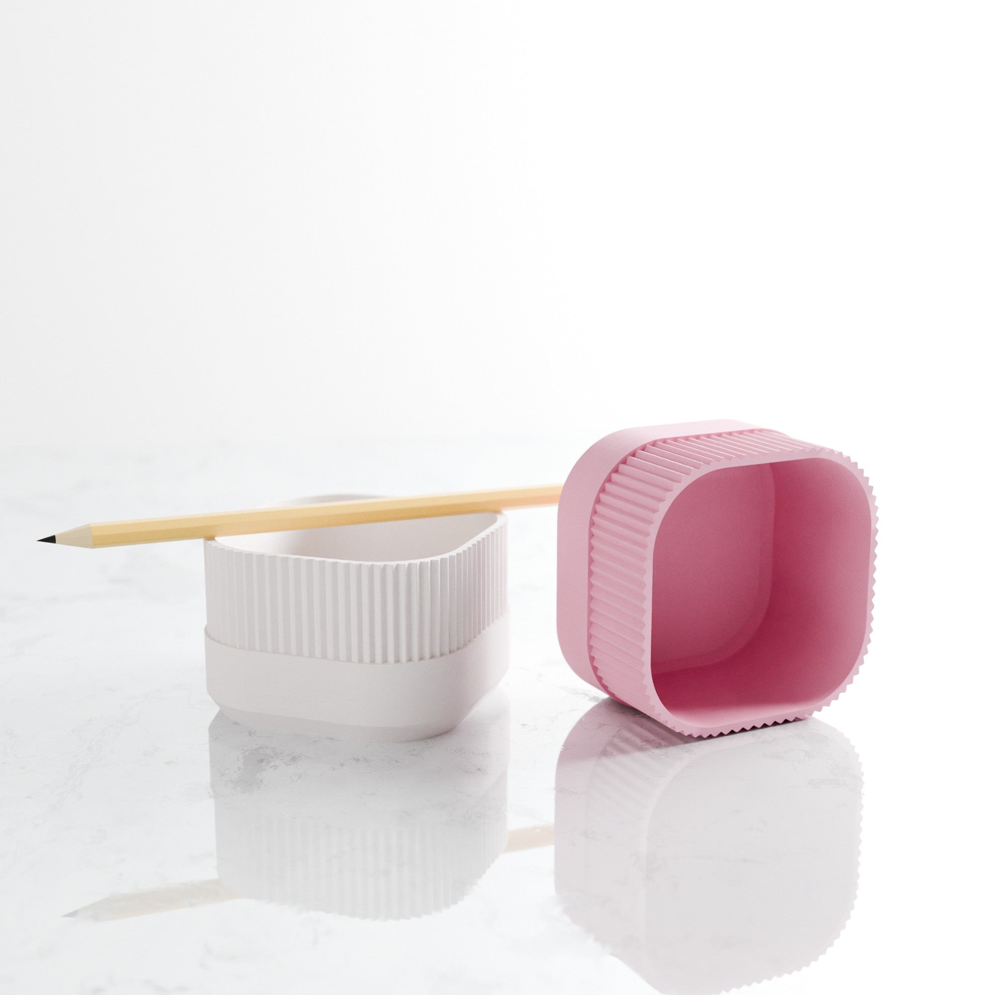 White and pink desk organizers with a pencil on a white background