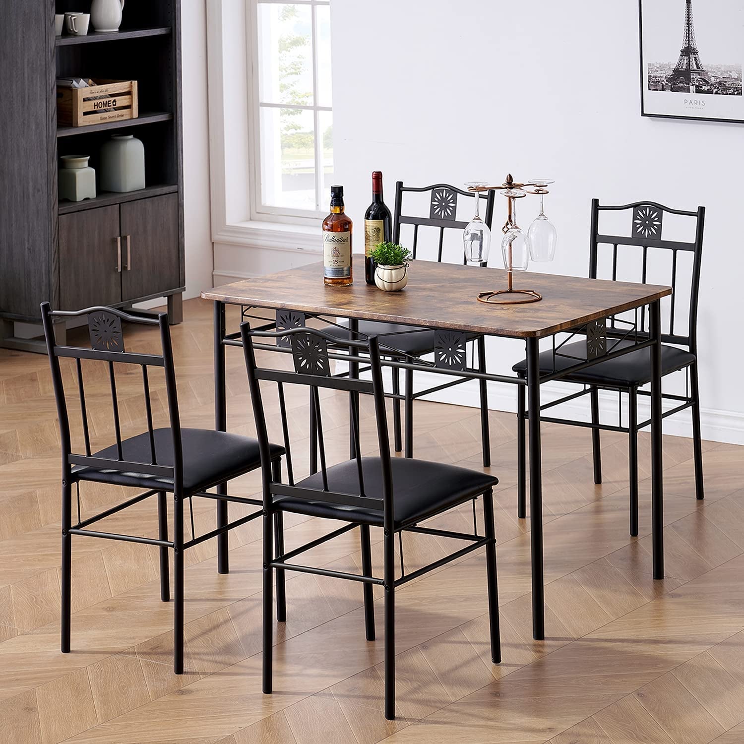 Dining table set with four black chairs in a room with a bookshelf and window.