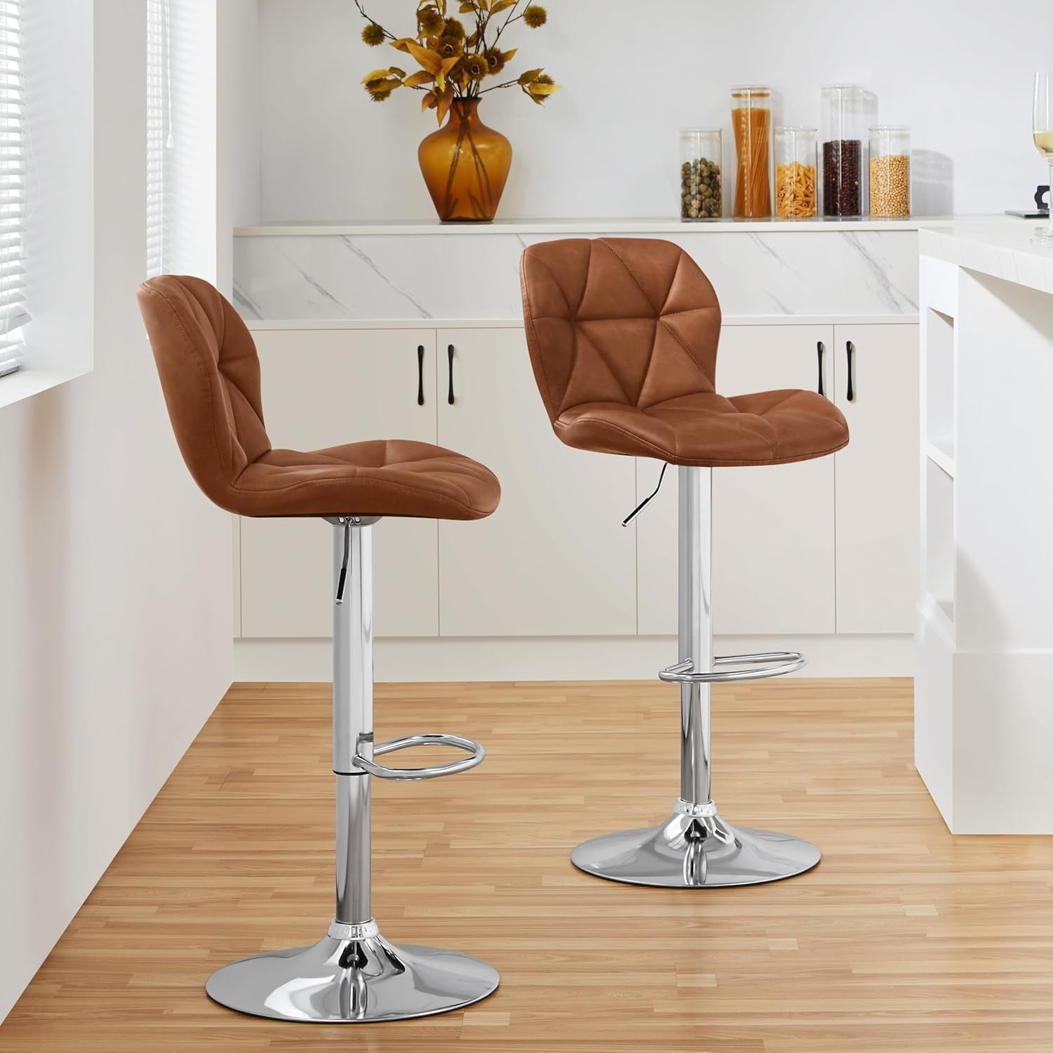 Two brown bar stools with chrome bases in a kitchen setting.