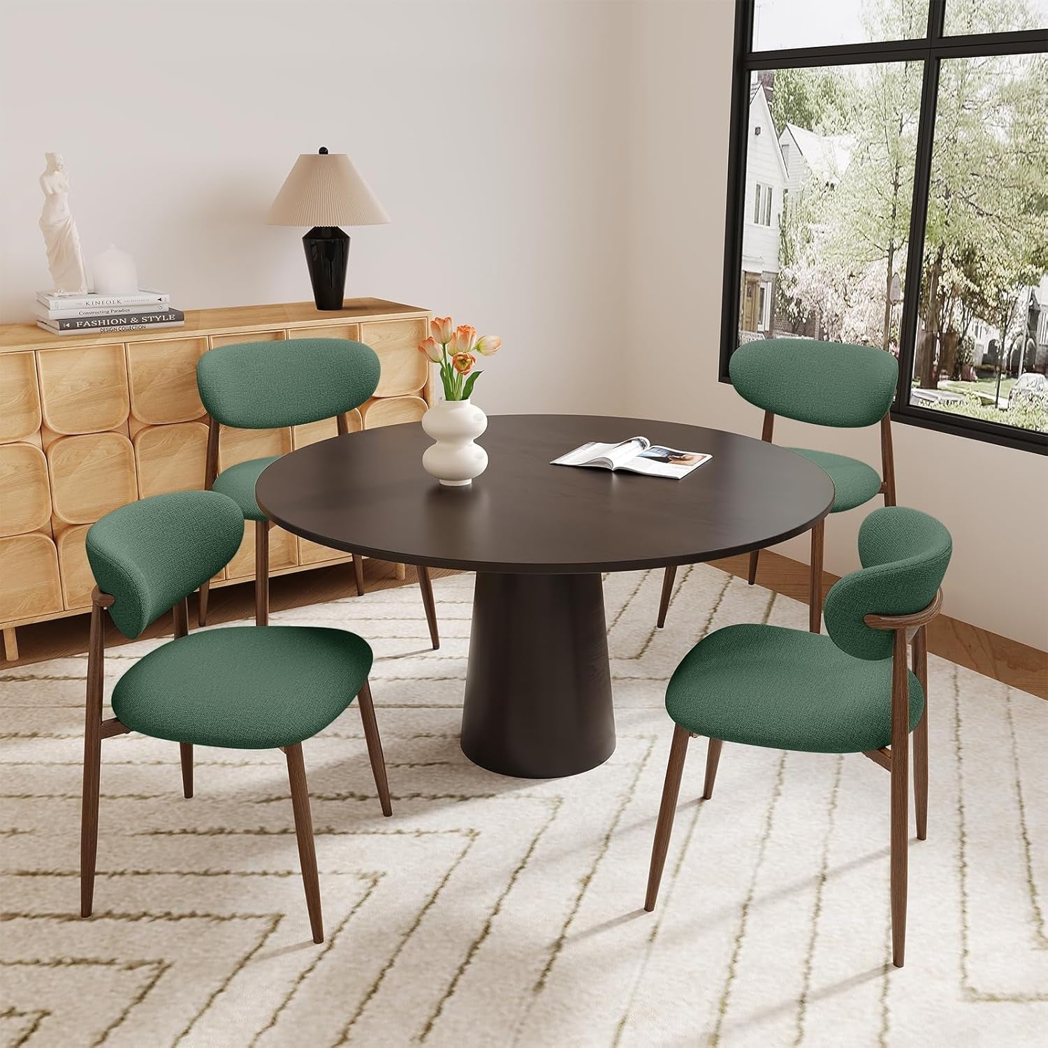 Dining room with a round dark brown table and green chairs, featuring a lamp and decorative items on a wooden sideboard.
