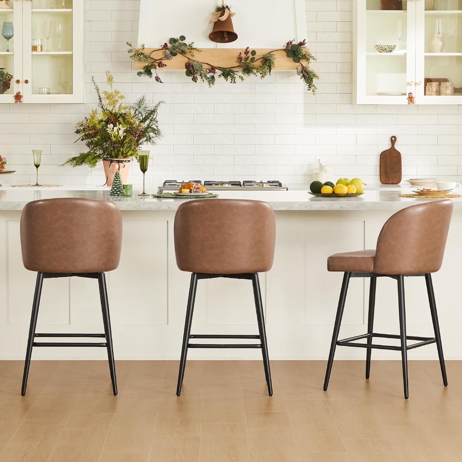 Three brown bar stools in a kitchen setting with a white island and decorative elements.