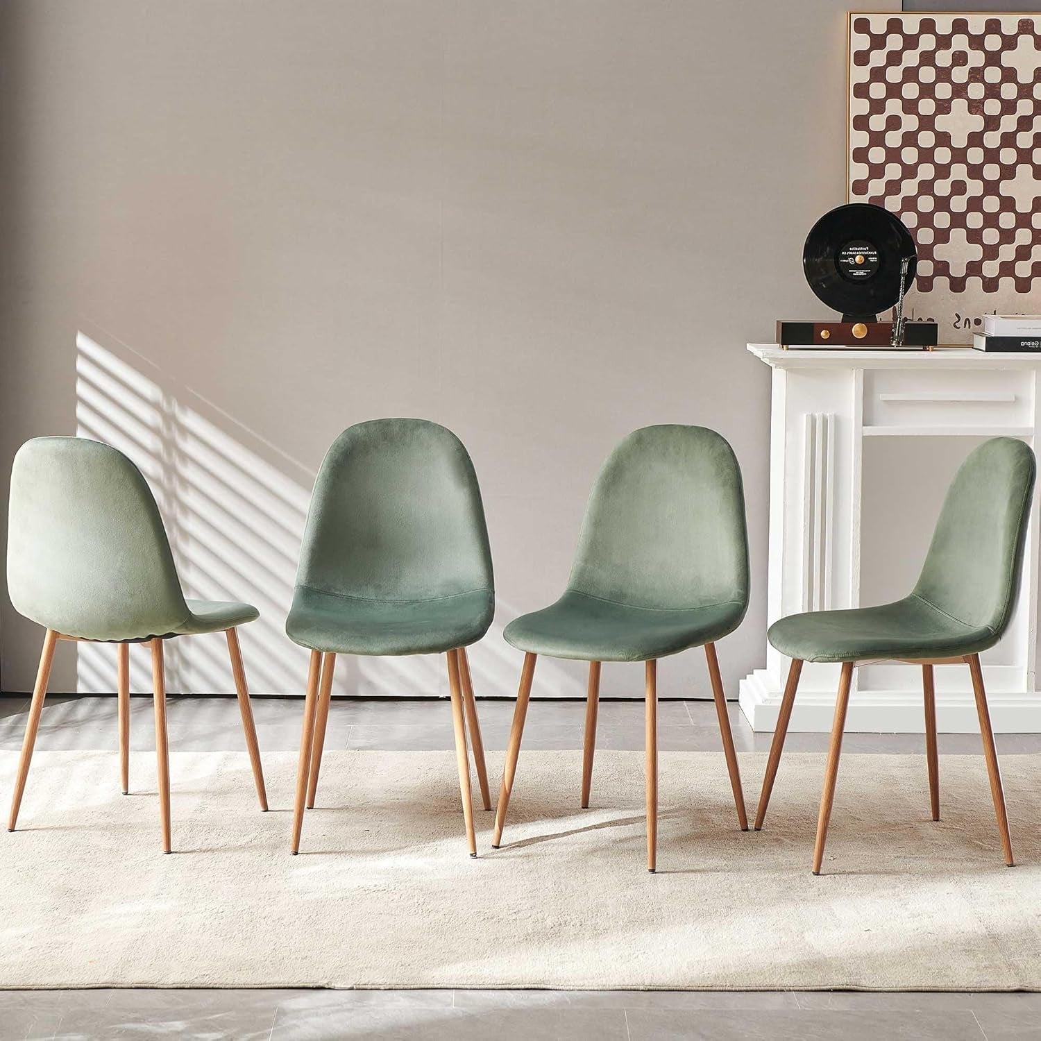 Four green chairs with wooden legs arranged in a row against a neutral wall.