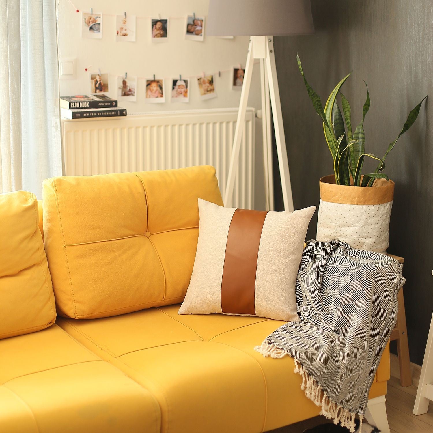 Yellow sofa with decorative pillows and a plant in a room.