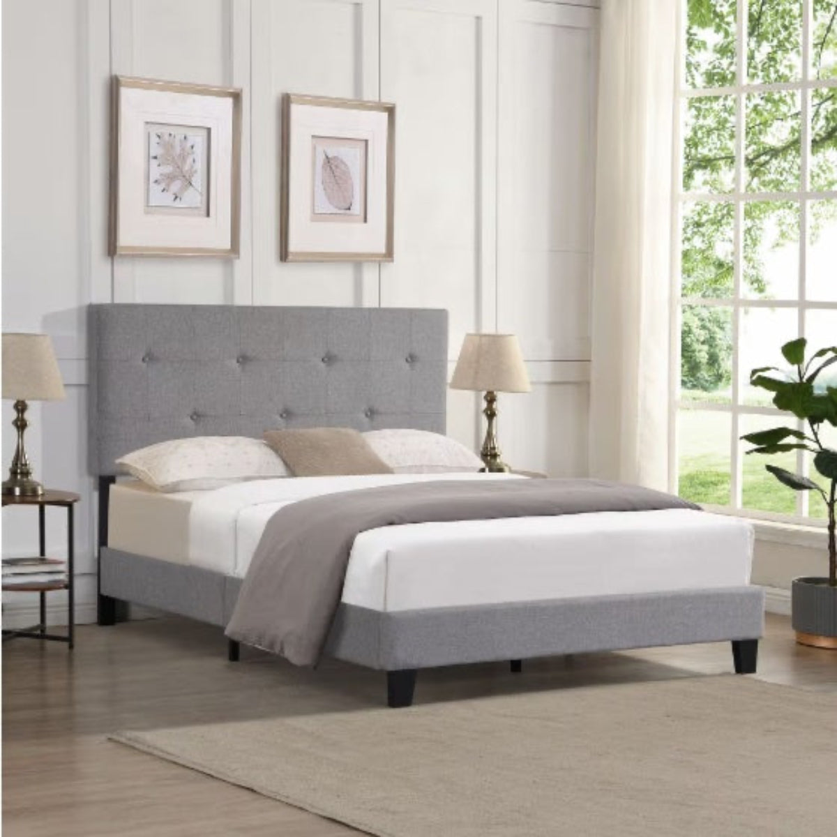 Gray upholstered bed in a well-lit bedroom with decor elements.