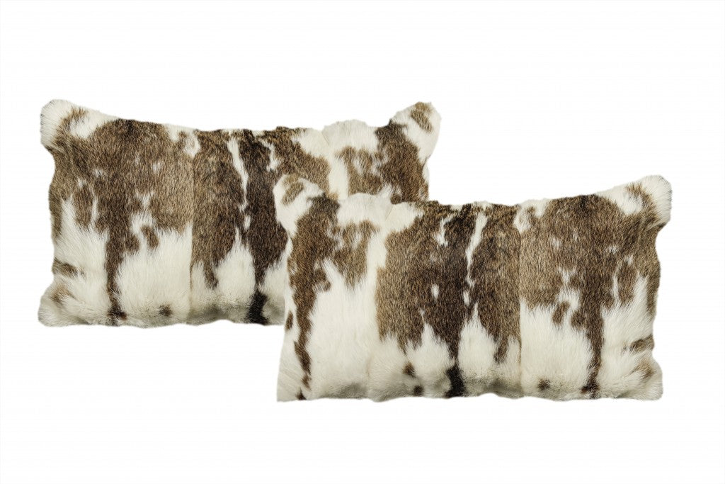Two cowhide patterned pillows on a white background
