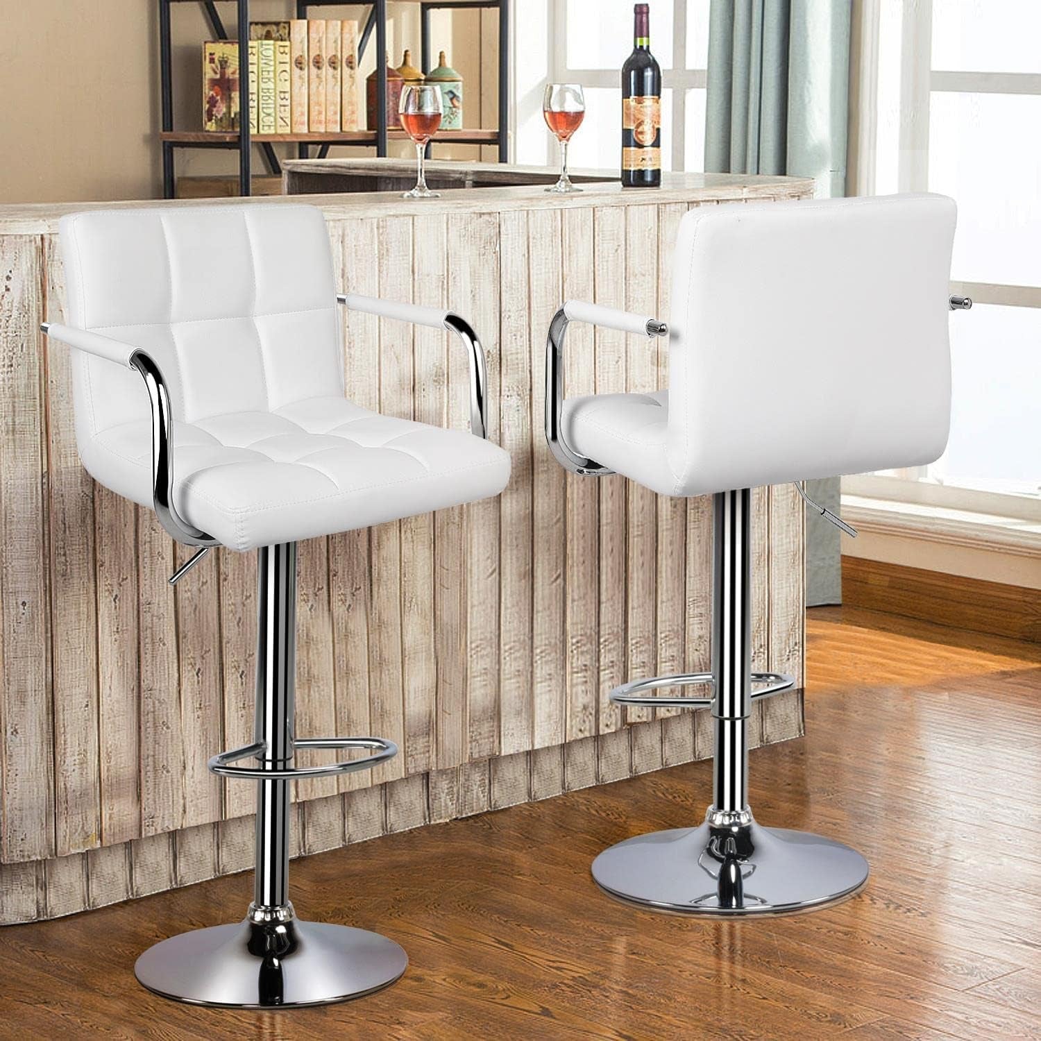 Two white bar stools with chrome bases in a room with wooden flooring and a bar counter.