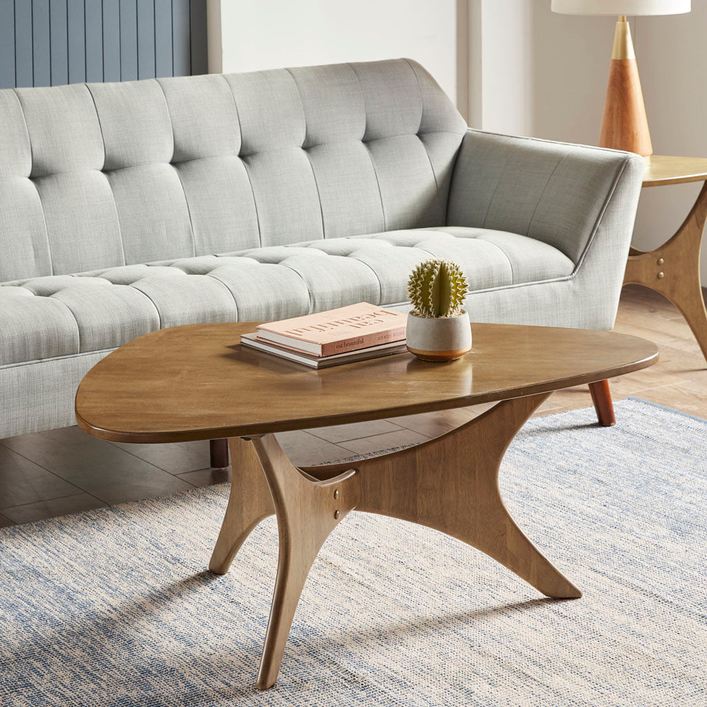 Wooden coffee table with a plant and books in a living room setting.