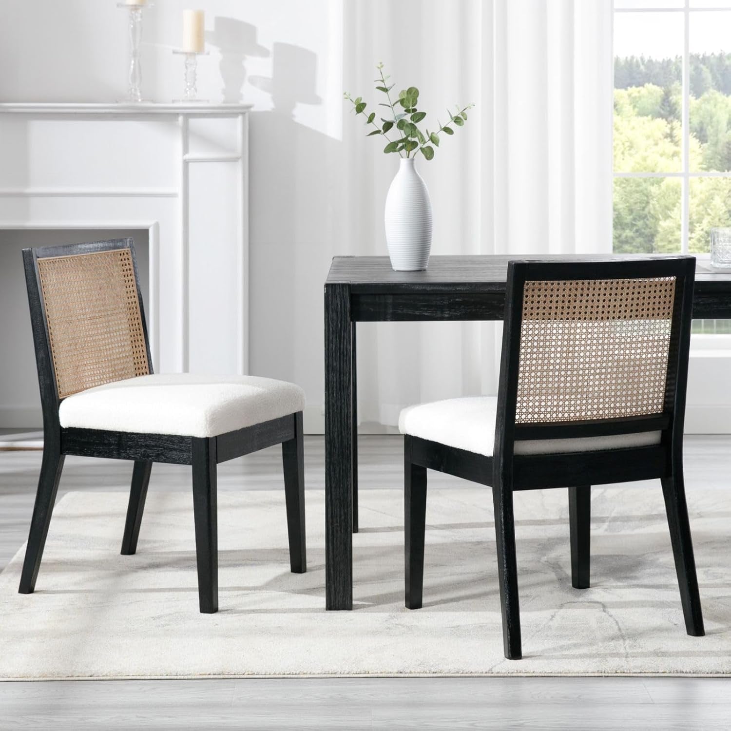 Dining table with two chairs in a room with a fireplace and window.
