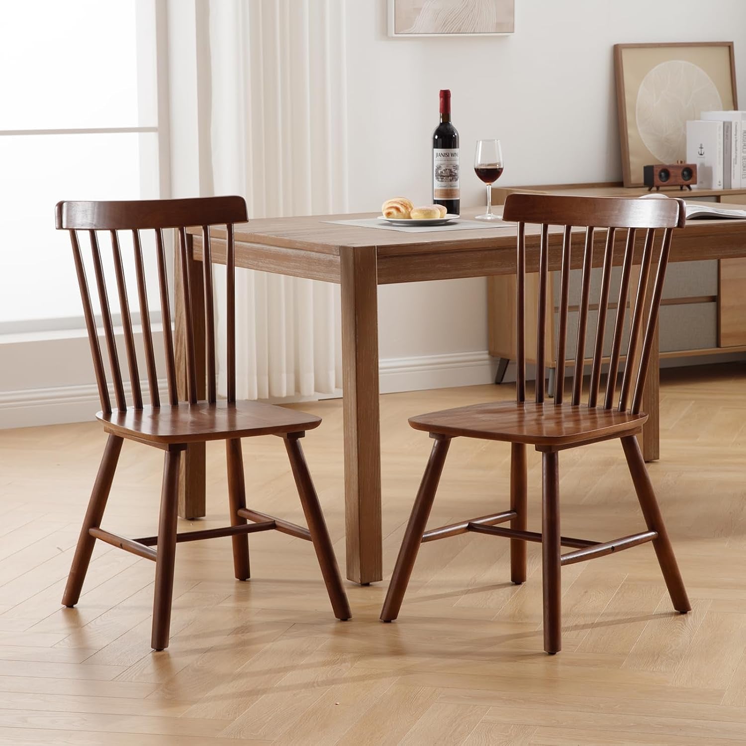 Wooden dining table with two chairs in a room with a window and decor.