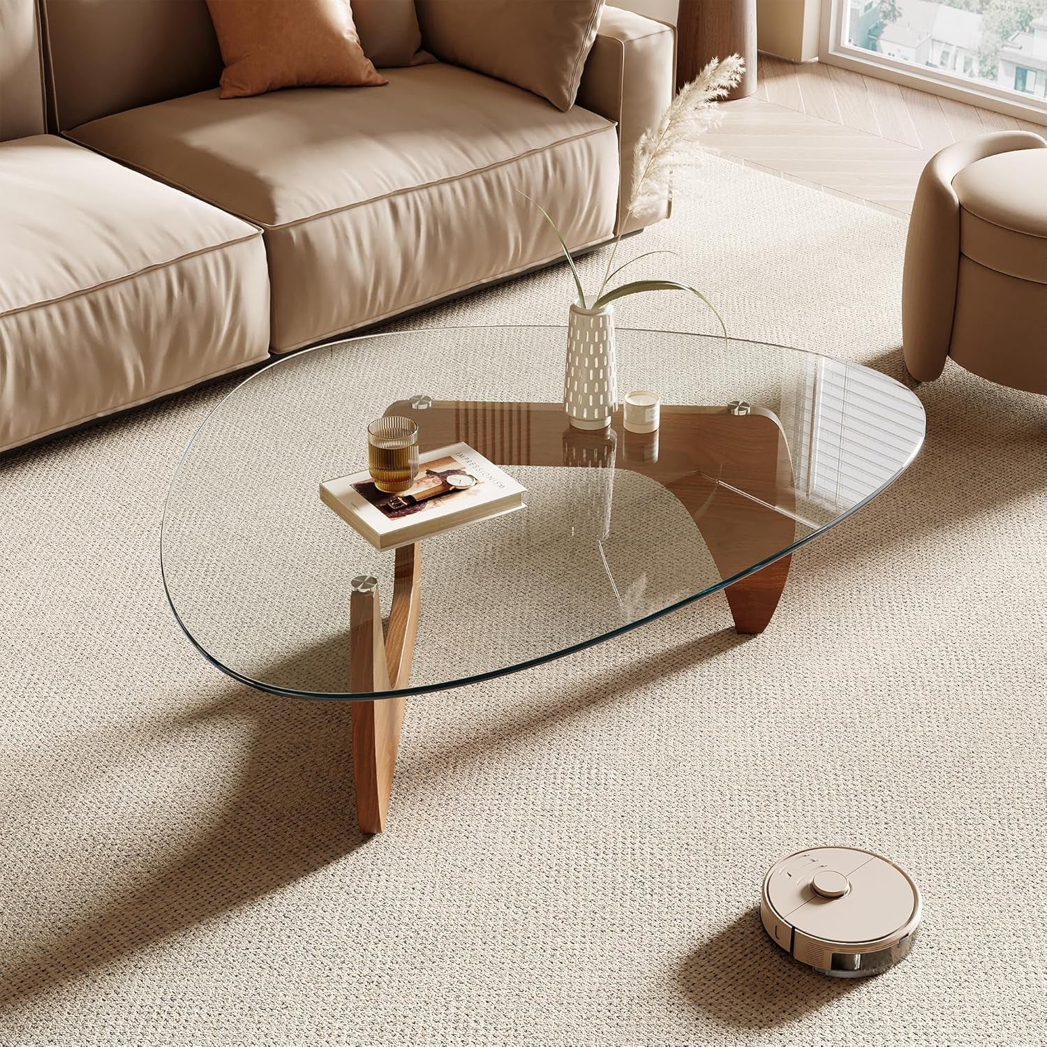Modern living room with a glass coffee table and a robot vacuum cleaner.