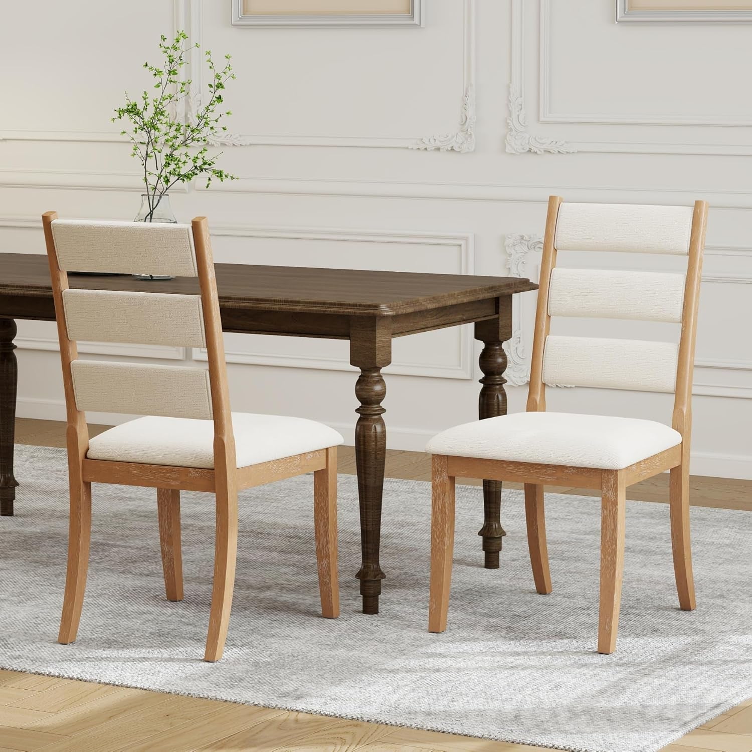 Dining table with two wooden chairs in a room with light-colored walls and a rug.