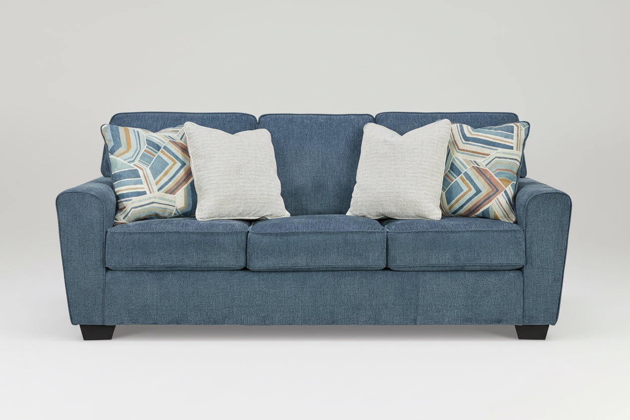 Blue sofa with patterned and plain cushions on a white background