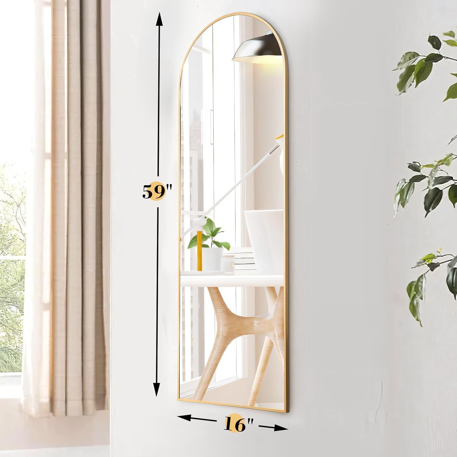 Full-length mirror with dimensions on a white wall with a plant and window.