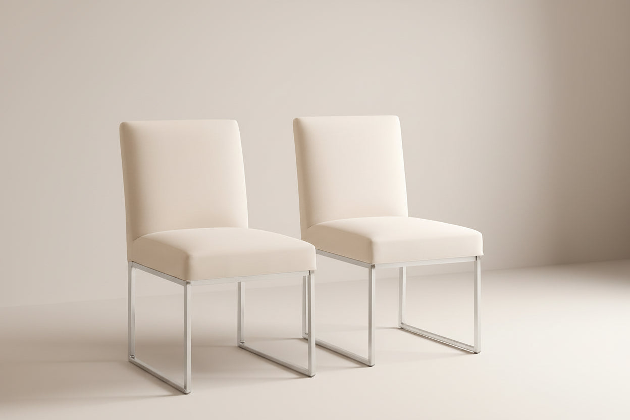 Two beige chairs with metal legs on a beige rug against a beige wall.