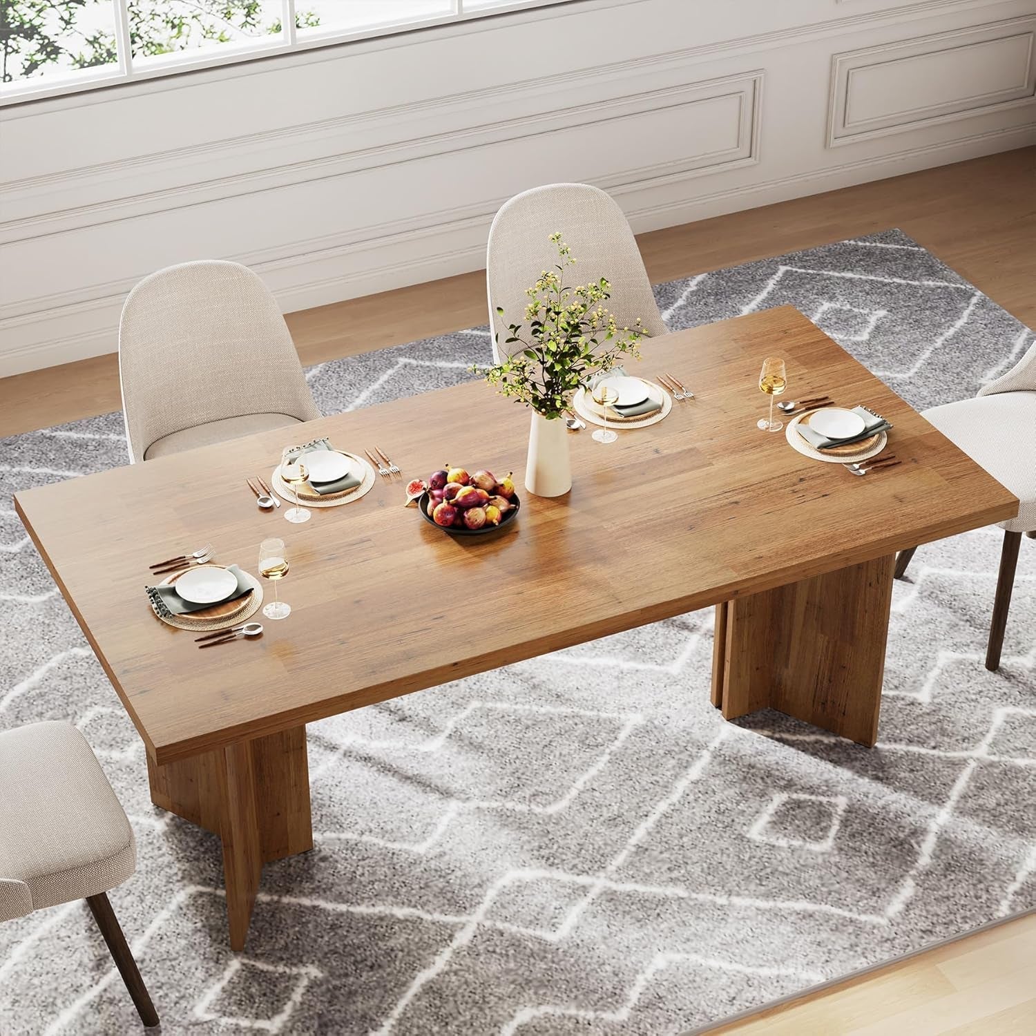 Dining table set with plates, glasses, and a vase of flowers in a room with a window and rug.