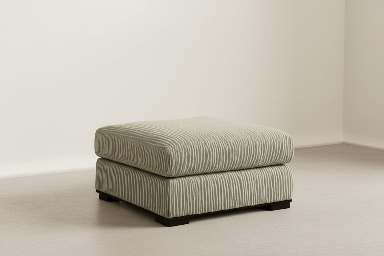 Patterned ottoman on a beige carpet with a brown wall and small table in the background