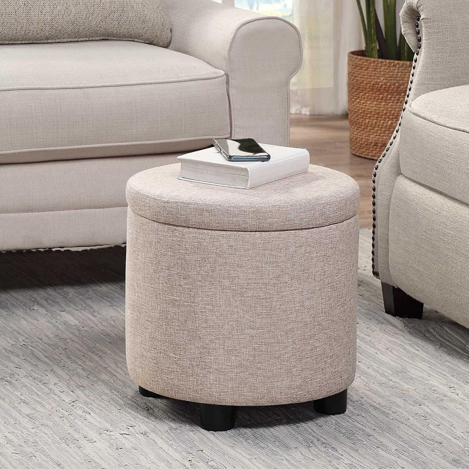 Beige ottoman with a book and phone on top in a living room setting