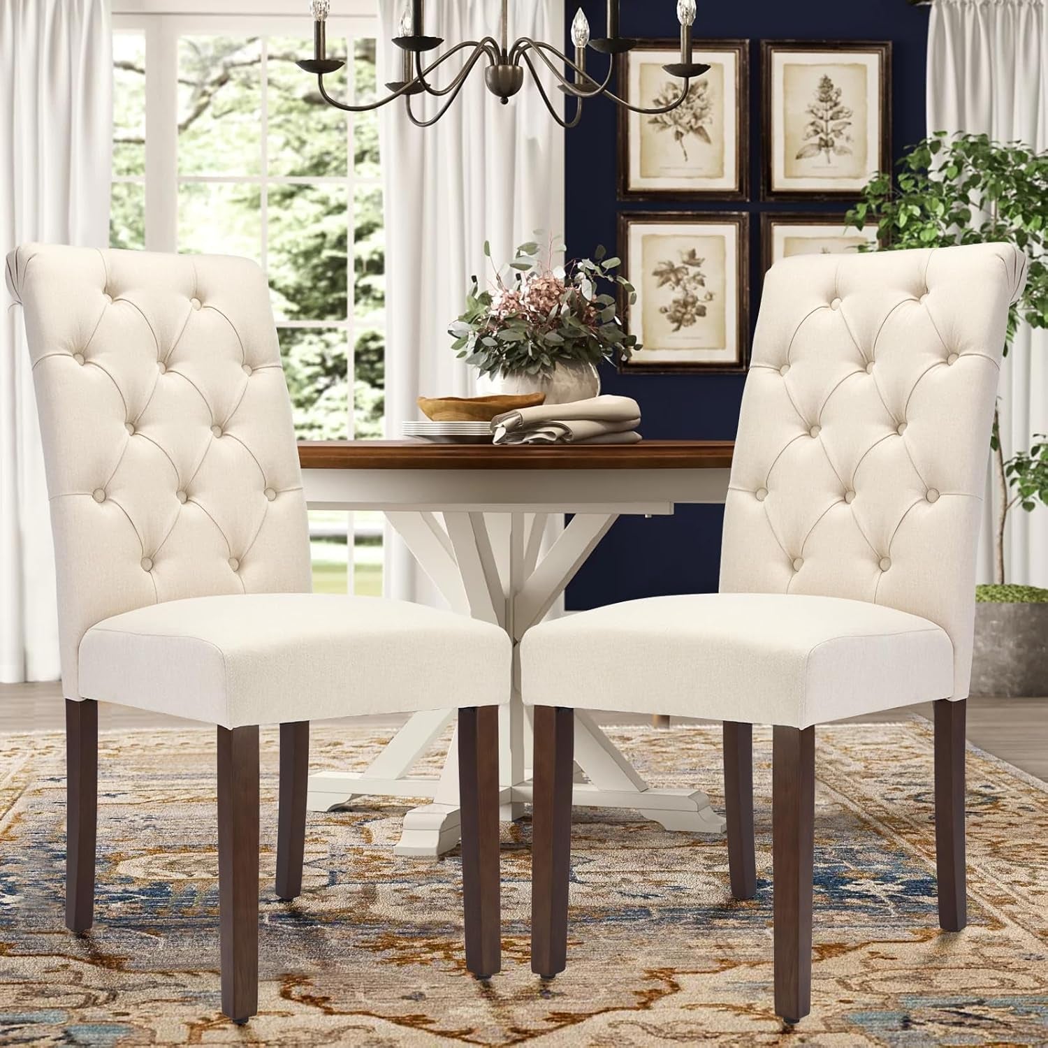 Dining room with two white tufted chairs and a round wooden table.