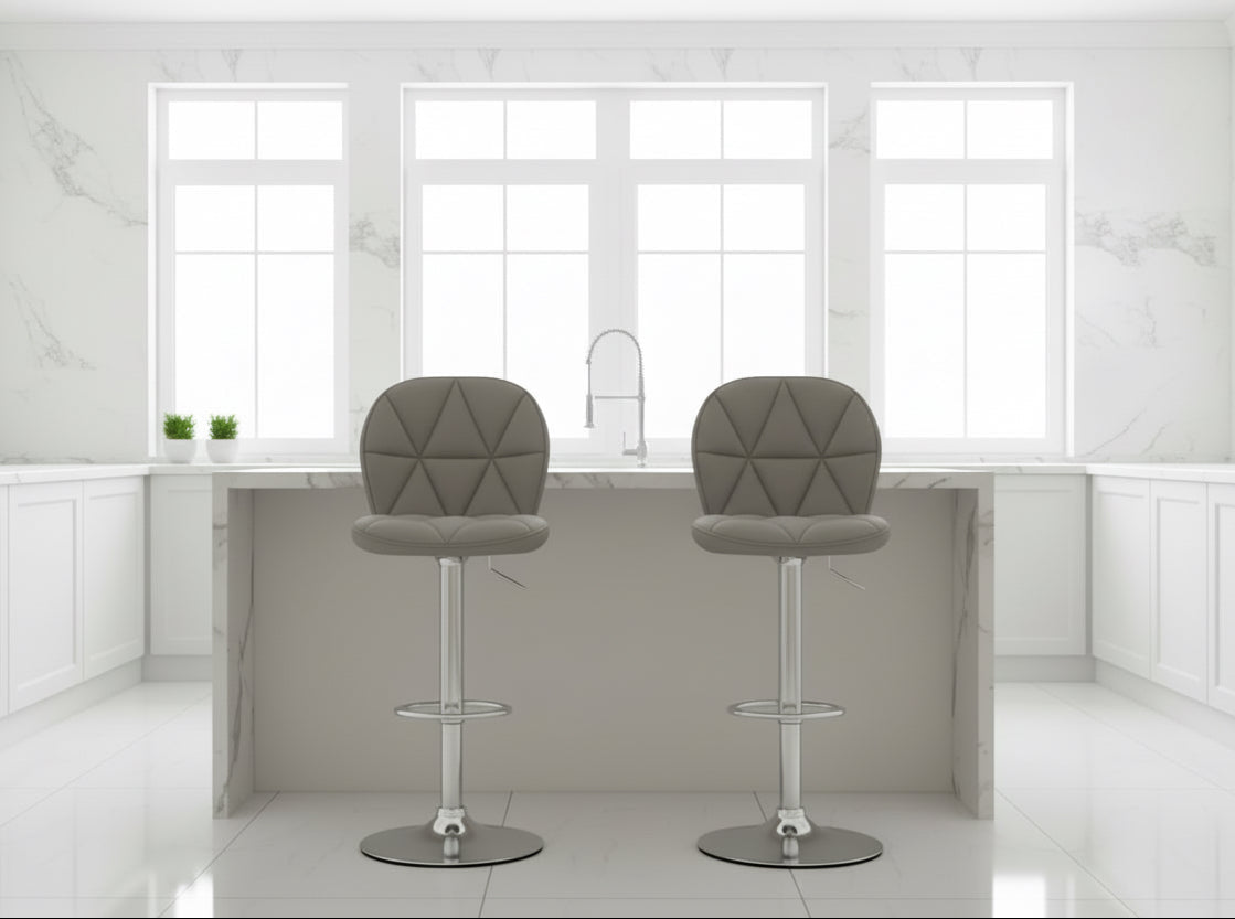 Two gray bar stools with quilted seats in a room with a beige wall and wooden furniture.
