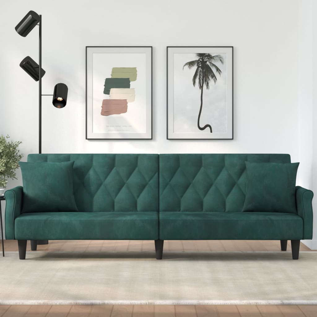 Green sofa in a room with wall art and a lamp.