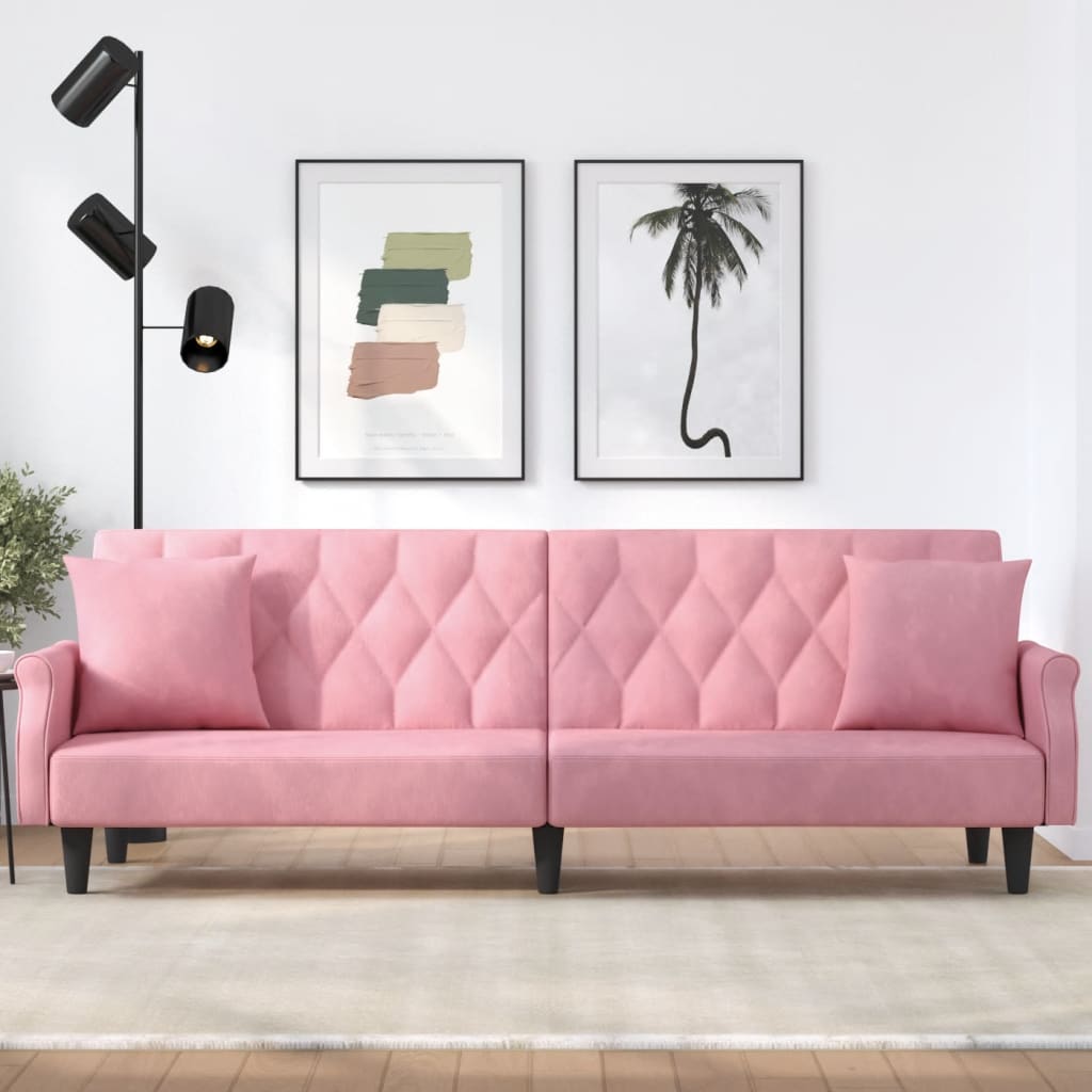 Pink sofa in a living room with wall art and a lamp.