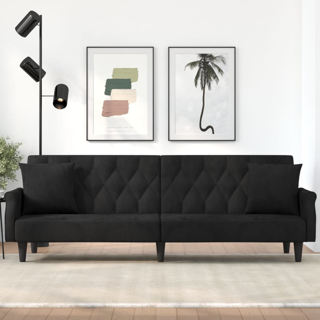 Black sofa bed in a room with wall art and a lamp.