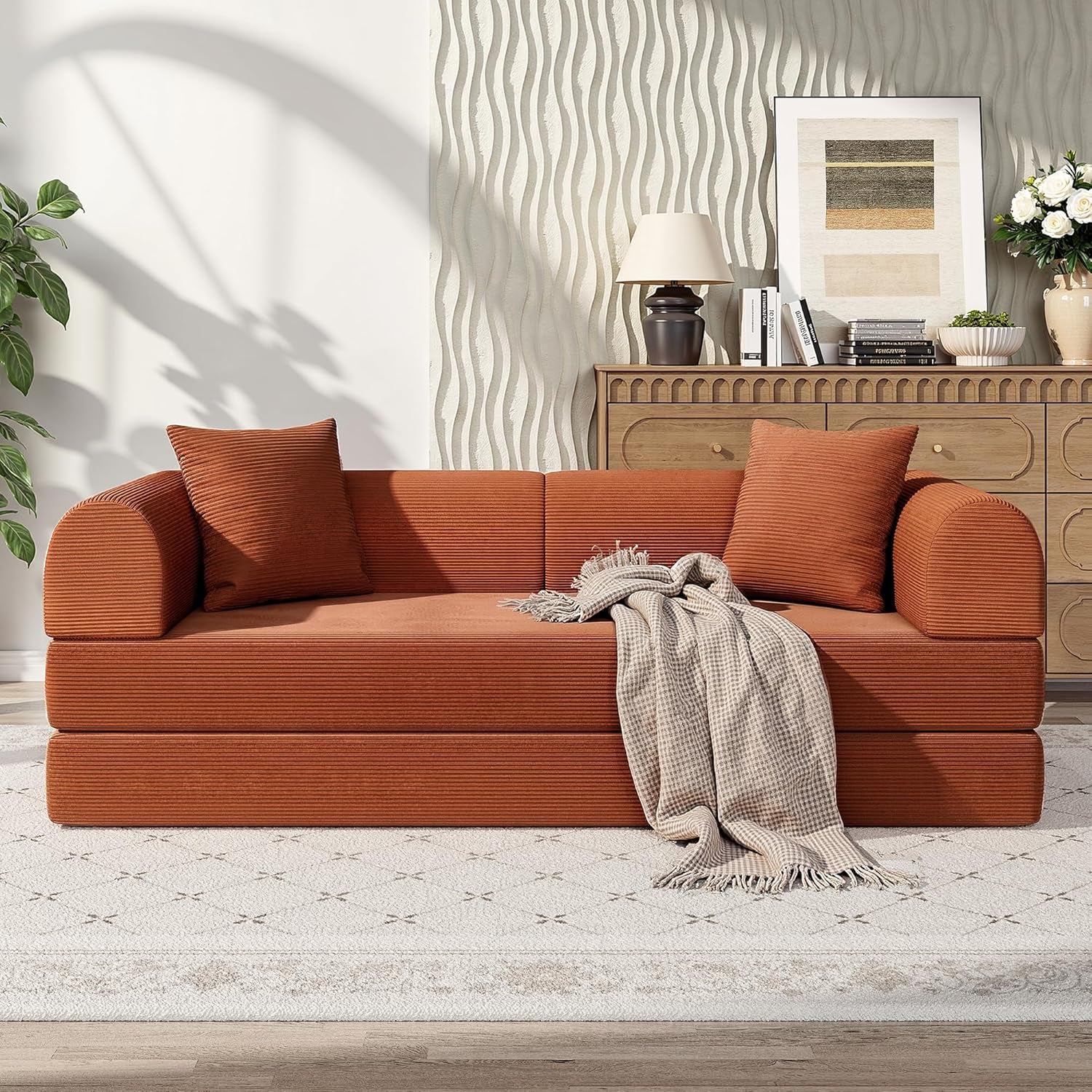 Orange sofa with cushions and a blanket in a living room setting.