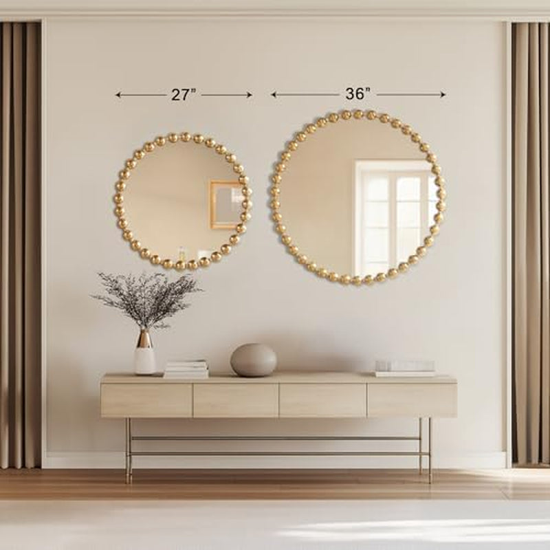 Two round mirrors with gold frames on a wall above a console table.