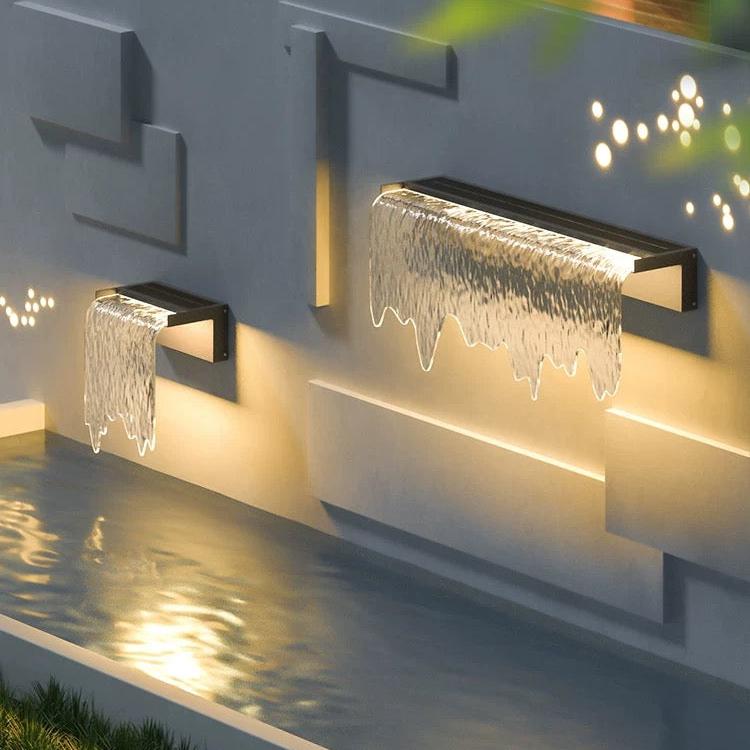 Modern outdoor wall lights with water feature on a concrete wall.