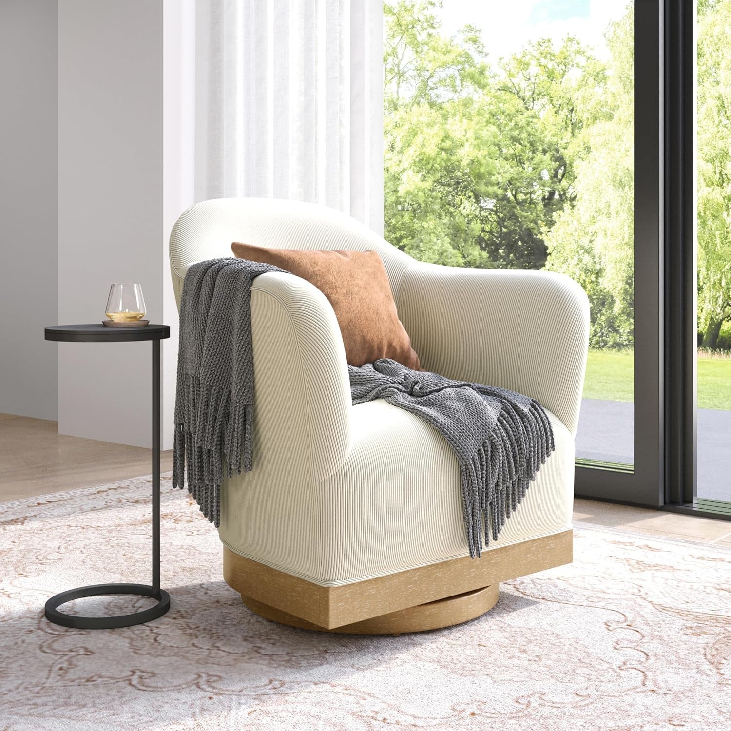 White armchair with a gray blanket and brown pillow in a room with large windows.