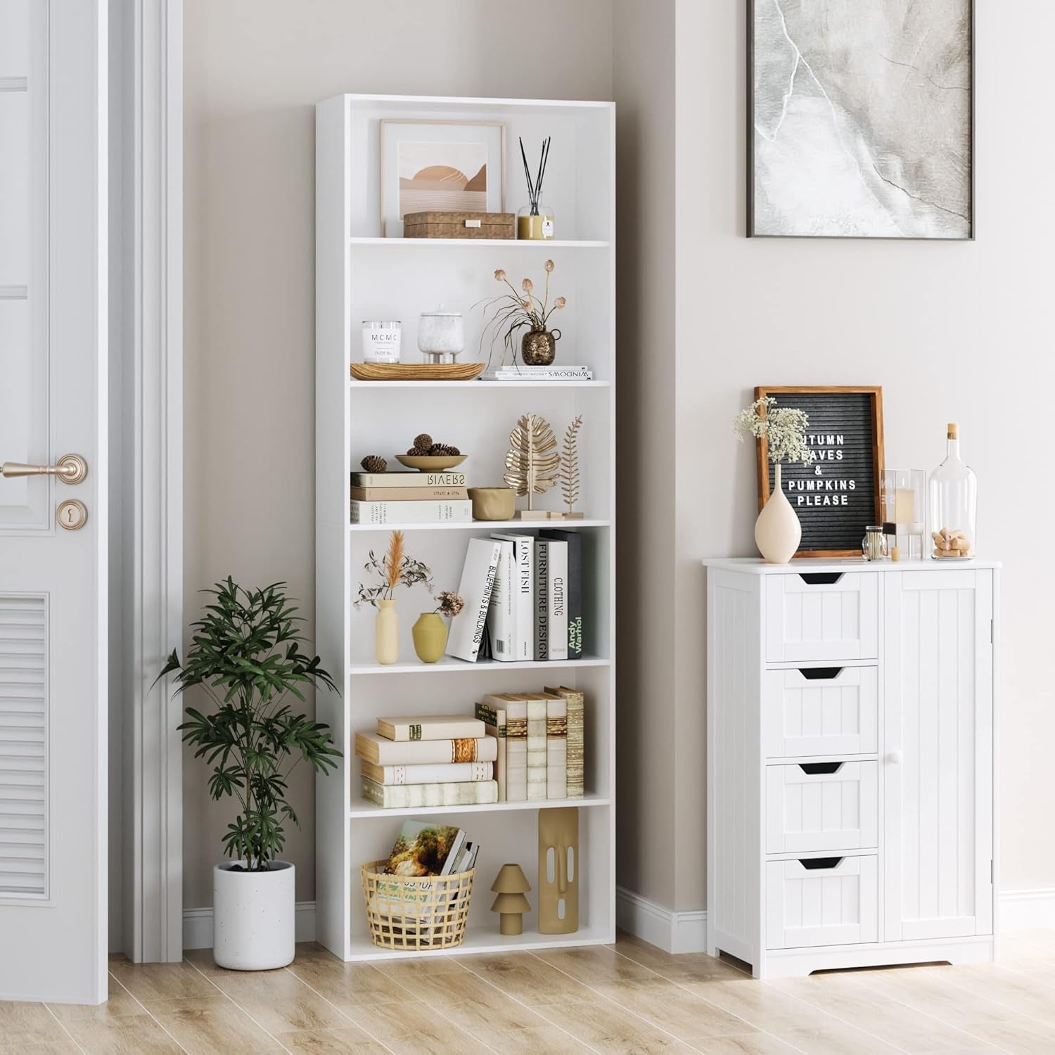 White bookshelf with decorative items in a room with a white cabinet and plant.