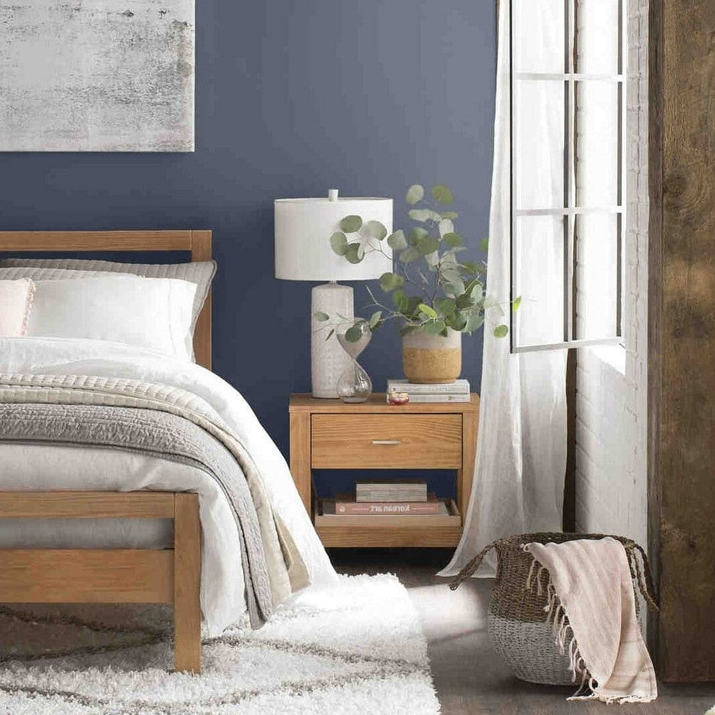 Modern bedroom with wooden bed, nightstand, and abstract art on a blue wall.