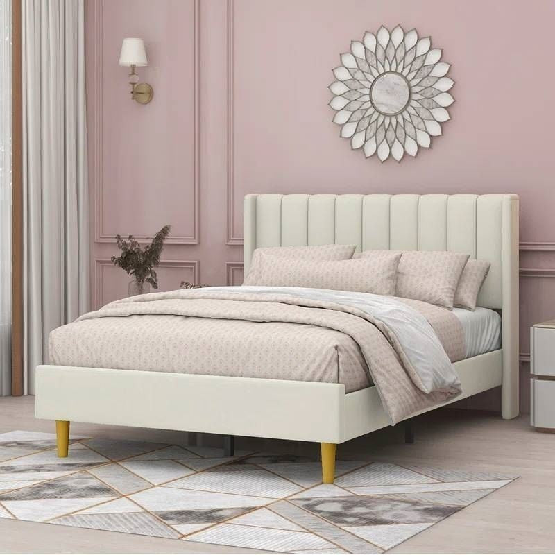 Beige upholstered bed in a room with pink walls and decorative elements.