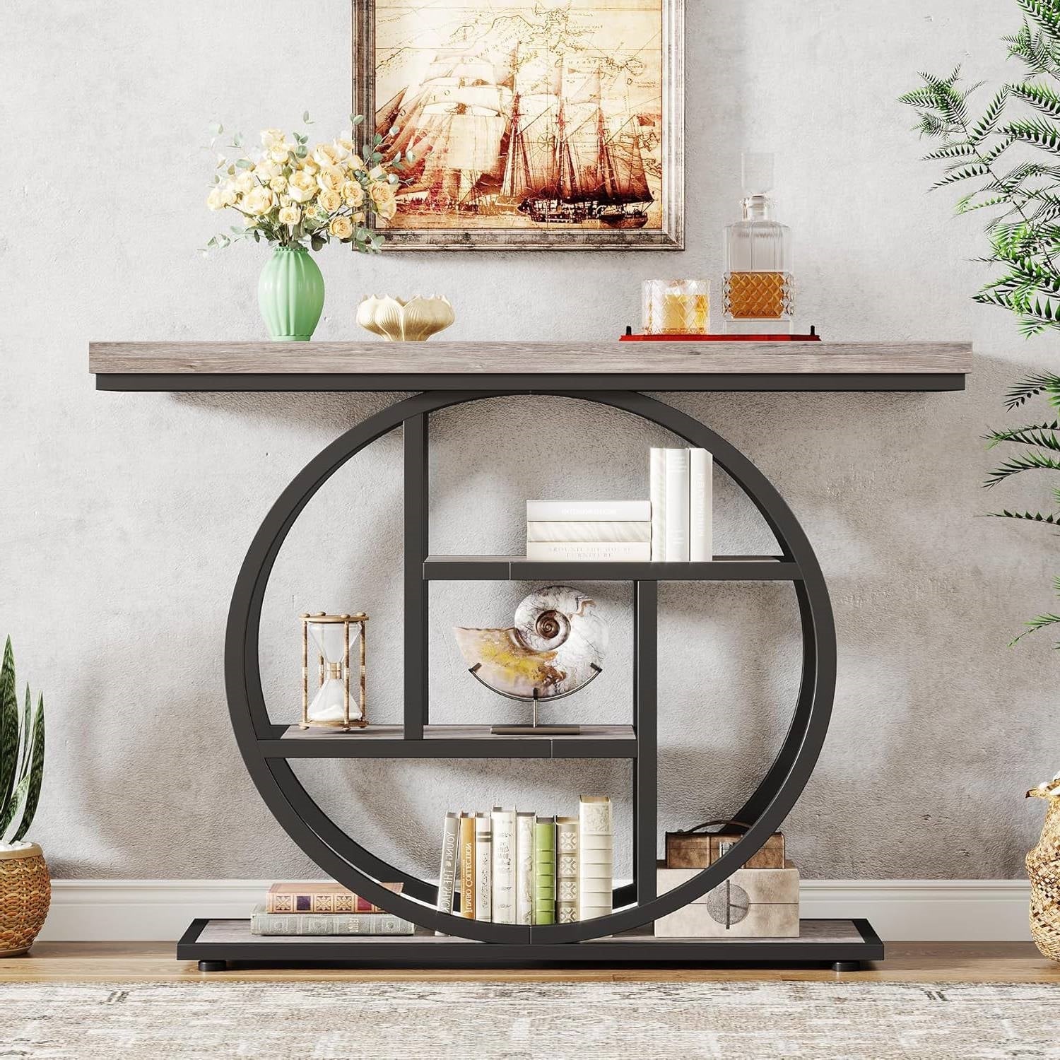 Decorative console table with circular metal shelf against a wall with a painting and plants.