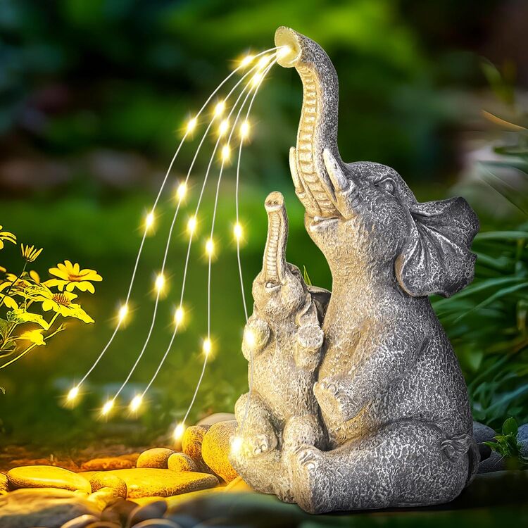Decorative elephant sculpture with string lights in a garden setting