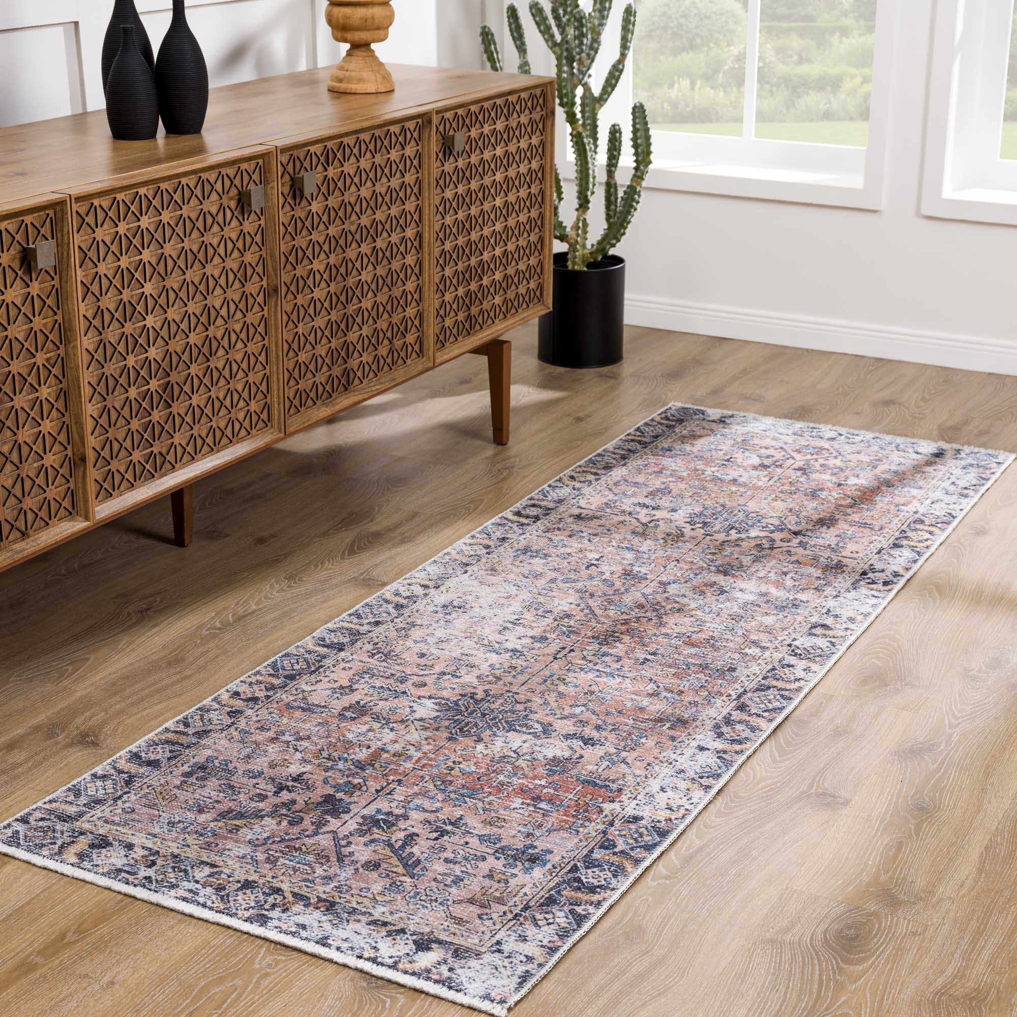 Long rectangular rug on a wooden floor in a room with a wooden sideboard and decorative items.